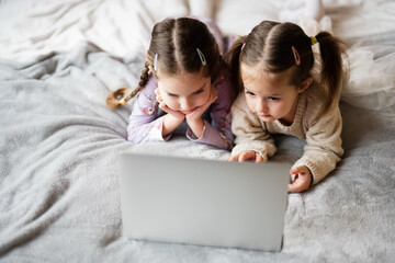 Two girls sisters watching on laptop. Technology and home concept.