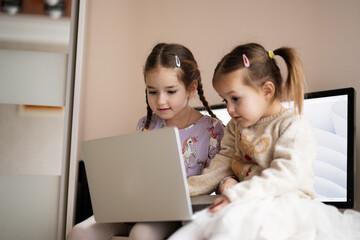 Two girls sisters watching on laptop. Technology and home concept.