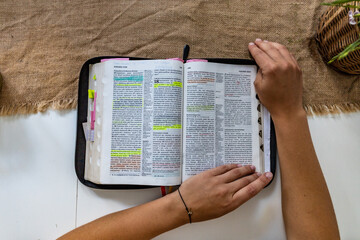 Reading Holy Bible with colorful highlights on pages which is lie on wooden table