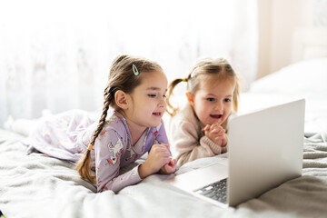 Two girls sisters watching on laptop. Technology and home concept.