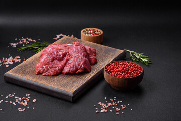 Raw beef cut into several pieces on a wooden cutting board
