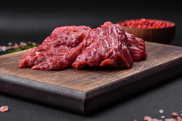 Raw beef cut into several pieces on a wooden cutting board