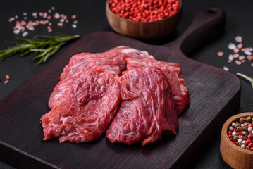 Raw beef cut into several pieces on a wooden cutting board