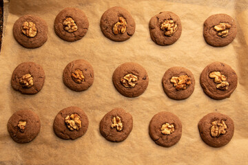 Warm vegan walnut and chocolate cookies on parchment paper with top down composition