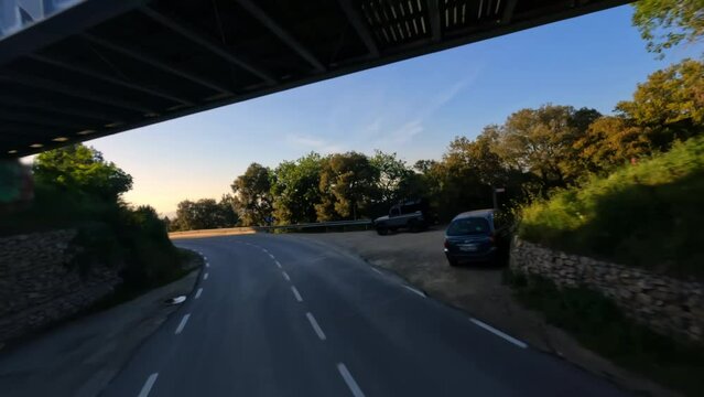 Dynamic fpv drone shot chasing Motorcycle driving under the bridge while sunset