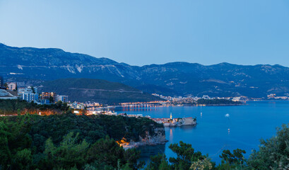 Fototapeta na wymiar Night city with electric lights against the backdrop of slopes of the Montenegrin mountains and the starry sky near the Adriatic Sea