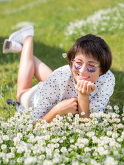 Woman in colorful sunglasses sniffs clover flowers on lawn in urban park. Nature in town. Relax outdoors after work. Summer vibes.