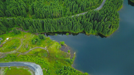 Aerial drone view about a part of a mountain lake. Rainy day, wet atmosphere. Coniferous trees...