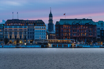Fototapeta premium Blick auf die St. Michaelis Kirche von Hamburg zwischen den Häusern an der Binnenalster hindurch zur blauen Stunde, horizontal 
