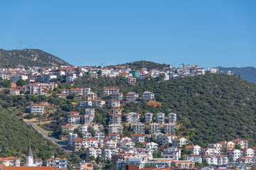 Obraz premium Majestic panoramic view of seaside resort city of Kas in Turkey. Hillside with traditional houses in the city, Villas and hotels with red roofs are open for tourists.