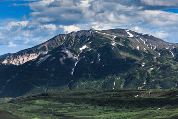 Obraz premium Green mountains interspersed with snow, landscape, clouds, sun, Kamchatka.