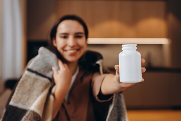 Happy young woman holding bottle of dietary supplements or vitamins in her hands. Close up. Healthy lifestyle concept