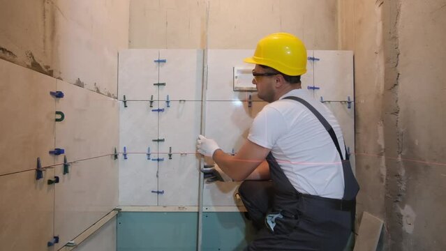 During the renovation of the bathroom, the builder lays the tiles. 