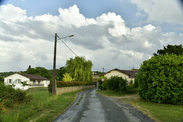 Route de campagne après une petite averse sous un ciel orageux au bourg de Champagne au Périgord...