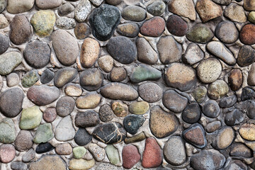 Textured stone wall with multicolored and different shaped stones.