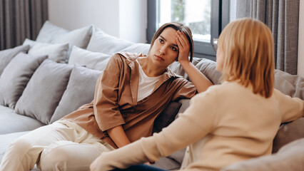 Naklejka na ściany i meble A young woman in a consultation with a professional psychologist listens to advice on improving behavior in life. The modern millennial woman is developing mindfulness and psychological health