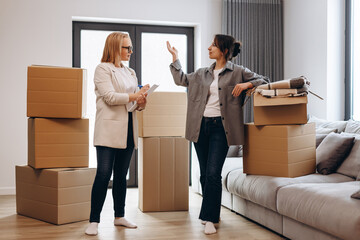 A young girl moves into her house. The realtor shows her the house. In the background are many moving boxes.