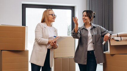 A young happy girl came to her new house where the realtor answers her questions and shows her the new house. The concept of moving.
