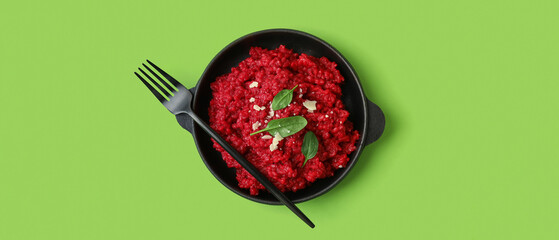 Frying pan with tasty beet risotto on green background