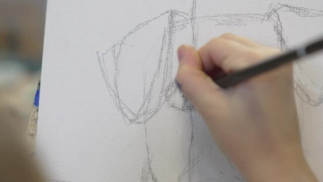 close up. a little girl makes a sketch with a pencil a painting in an art studio