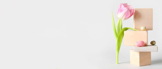 Empty podiums with Easter eggs and tulip flower on light background with space for text