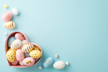 Fototapeta na wymiar Easter decorations concept. Top view photo of colorful easter eggs in heart shaped bowl on isolated pastel blue background with empty space