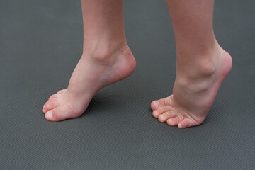 child is barefoot on mat. child does an exercise for feet, standing on tiptoes. Prevention of flat feet in children. Health care.