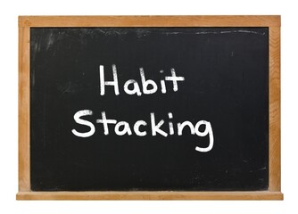 Obraz premium Habit stacking written in white chalk on a black chalkboard isolated on white