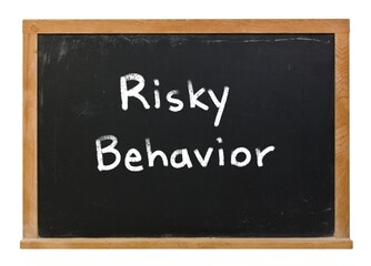 Fototapeta premium Risky behavior written in white chalk on a black chalkboard isolated on white