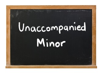Unaccompanied minor written in white chalk on a black chalkboard isolated on white
