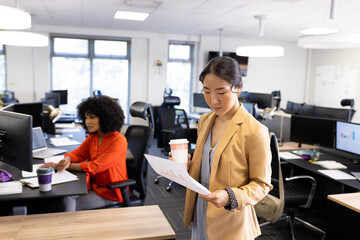 Asian businesswoman with documents and coffee working in office