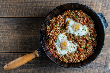 Boiled buckwheat with fried eggs, red peppers, carrots and onions, closeup, Ukraine. Food background. Healthy food