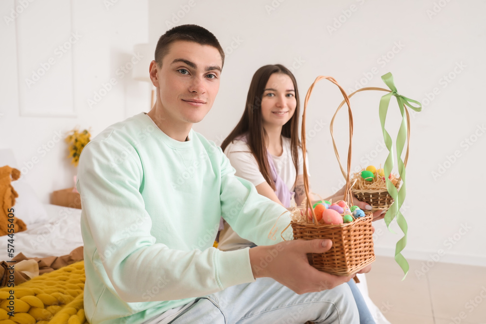 Sticker happy young couple with baskets of easter eggs in bedroom