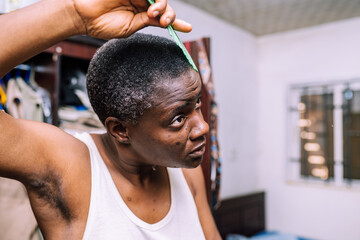 A queer masculine woman combing her hair