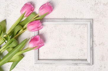 Beautiful tulip flowers and blank wooden frame on white grunge background