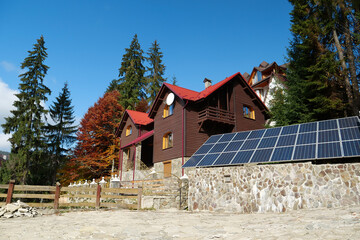 Renewable energy. Solar cell panels on fence near wooden house in village