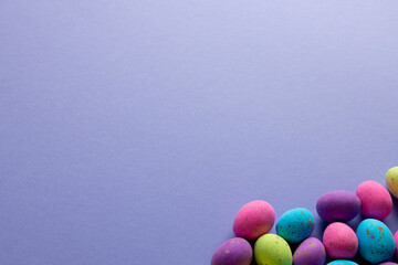 Image of multi coloured easter eggs with copy space on purple background