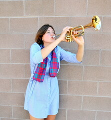 Female blowing her trumpet outdoors.