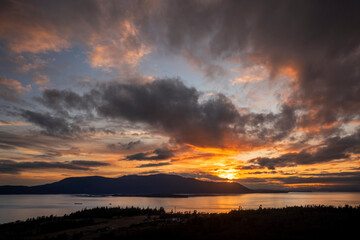 Dramatic Sunset Over Orcas Island, Washington. Aerial view of a Tugboat towing a barge through Rosario Strait between Lummi Island and Orcas Island in the San Juan Islands.