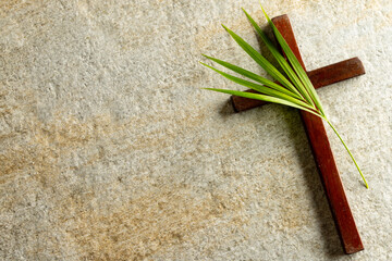 Image of close up of cross with palm leaf and copy space on stone background