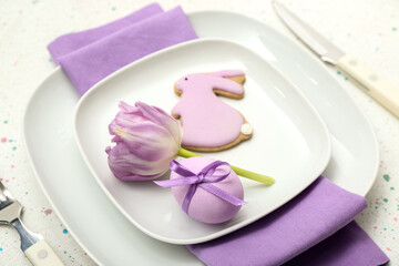 Table setting with Easter egg, bunny and tulip flower on white background