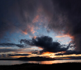 Dramatic Sunset Over Orcas Island, Washington. Aerial view of a Tugboat towing a barge through Rosario Strait between Lummi Island and Orcas Island in the San Juan Islands.