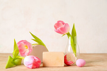 Composition with podiums, Easter eggs and beautiful tulip flowers on color table