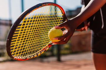 African american woman hold racket and yellow green ball, playing tennis match on clay court surface on weekend free time sunny day. Female player ready to serve. Professional sport concept

 - obrazy, fototapety, plakaty