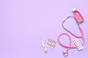 Stethoscope with thermometer and medications on violet background. World Health Day