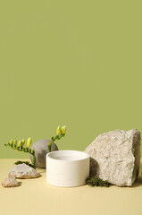 Plaster podium, stones and freesia flowers on green background