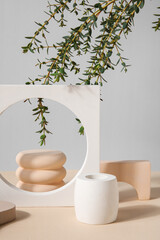 Plaster podiums and eucalyptus branches on beige table against grey background