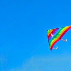 Rainbow kite flying in blue sky with clouds