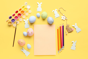 Blank paper sheet with paints, pencils, Easter eggs and rabbits on yellow background