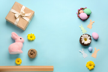 Frame made of gift, Easter eggs, rabbits and flowers on blue background